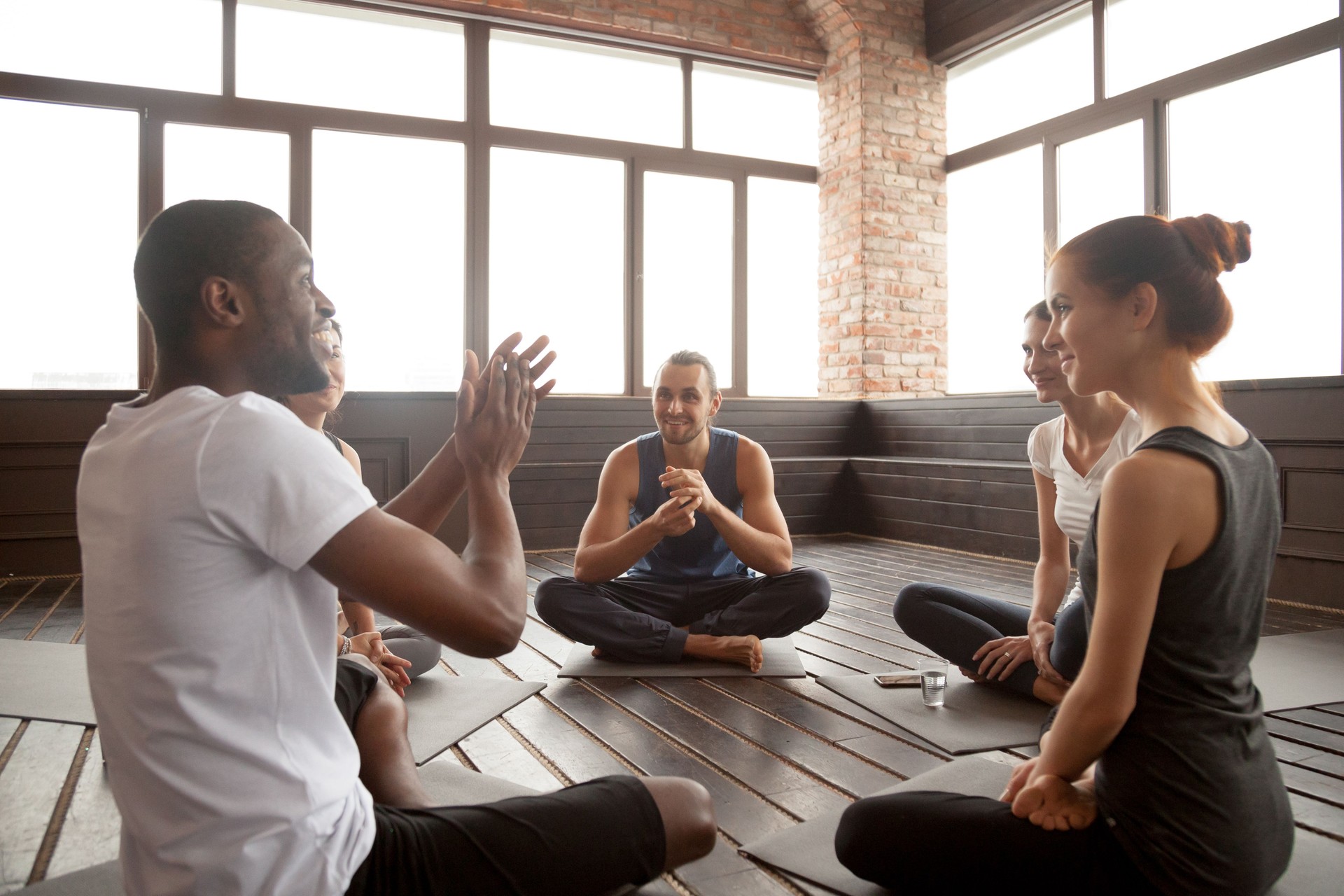 Excited african-american man talking to diverse friends sitting on mat